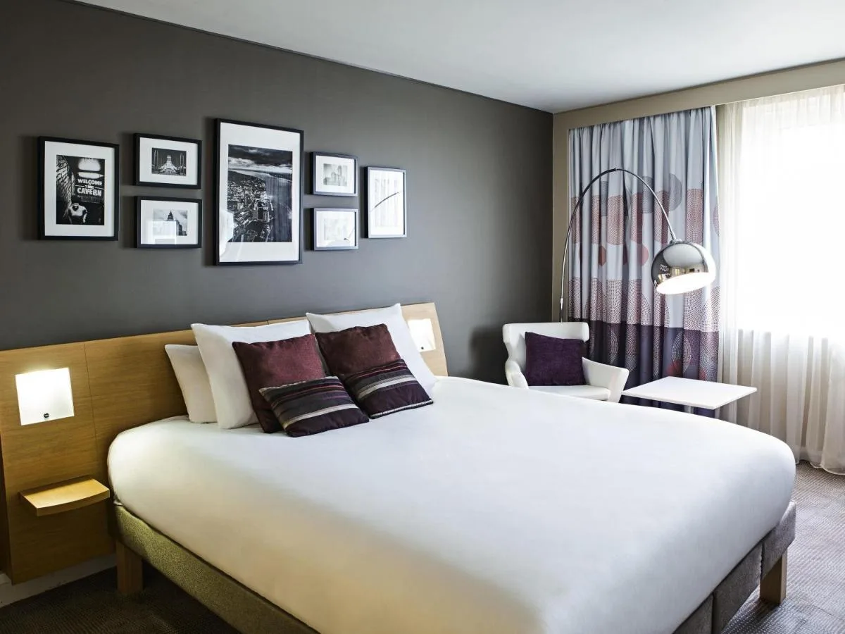 a bedroom with a large white bed and a chair at Novotel Liverpool Centre in Liverpool