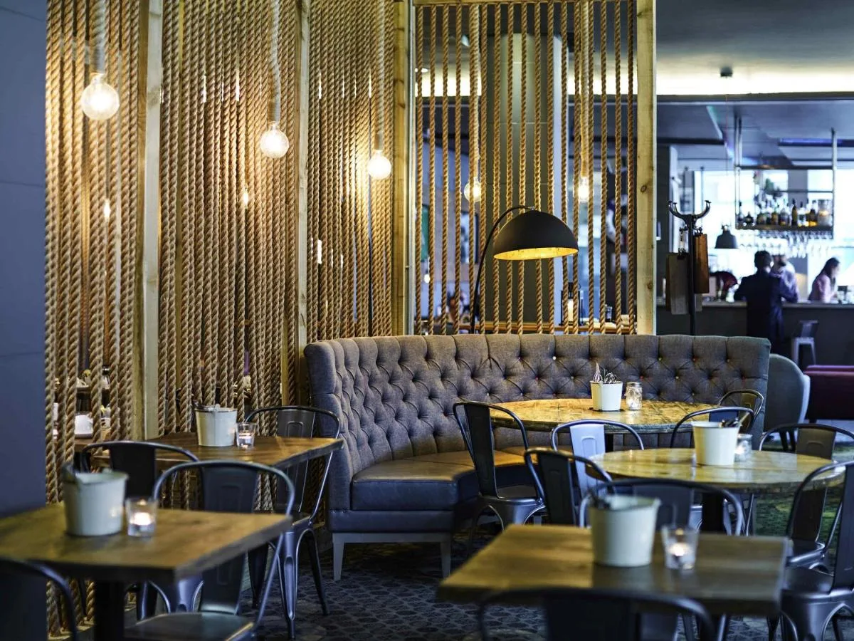 a restaurant with tables and chairs and a couch at Novotel Liverpool Centre in Liverpool